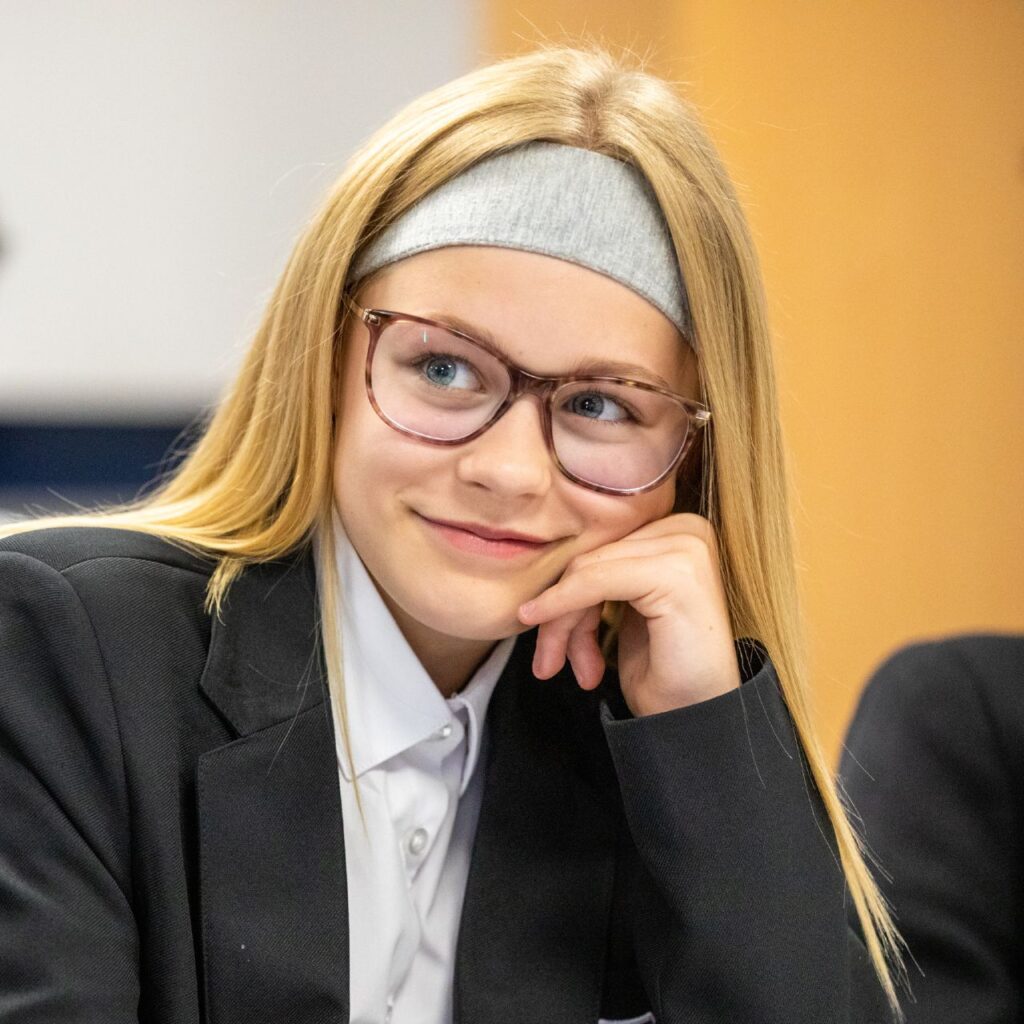 Blonde girl with glasses smiling in class