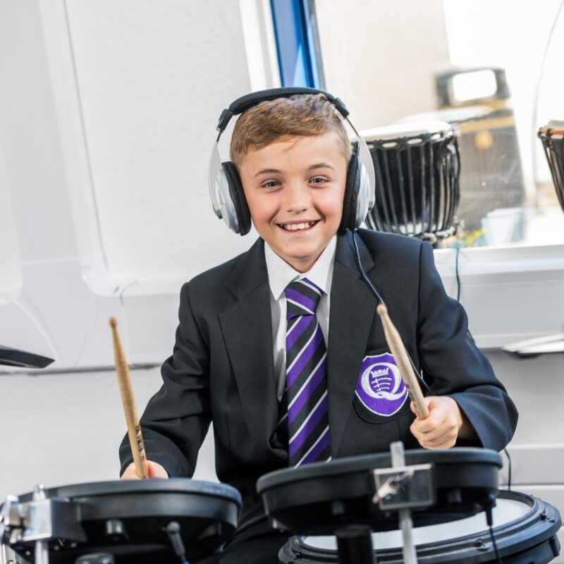 A smiling boy playing the drums