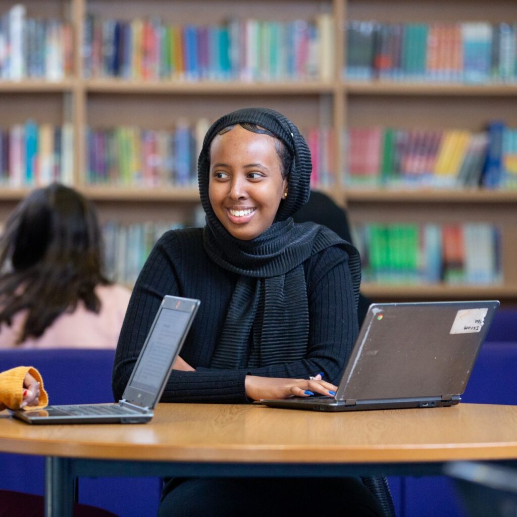 Teenage girl with a laptop in the library